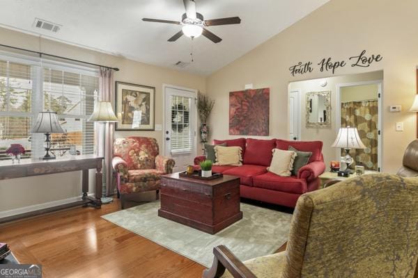 living room with lofted ceiling, wood finished floors, visible vents, and a wealth of natural light