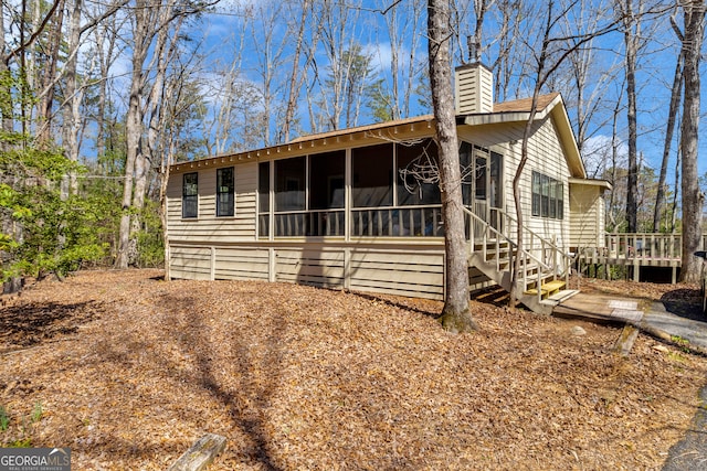 view of front of home with a chimney and a sunroom