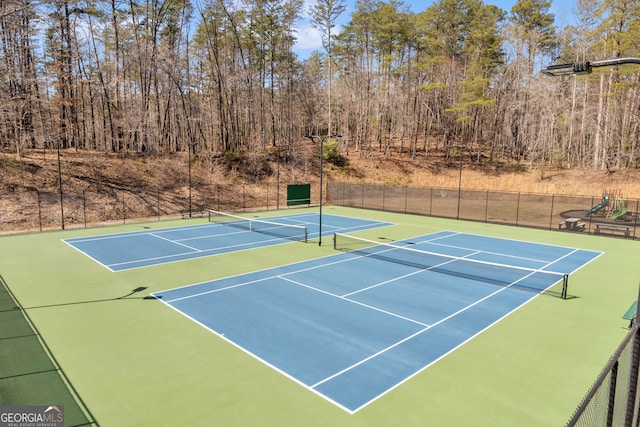 view of tennis court featuring community basketball court and fence