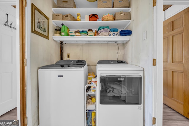 laundry room featuring laundry area, wood finished floors, and separate washer and dryer