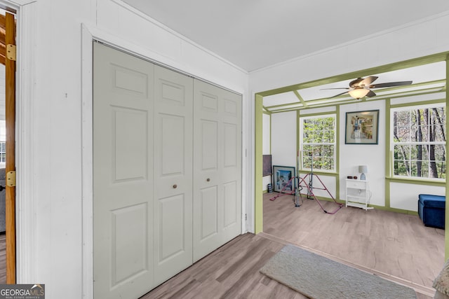 interior space featuring baseboards, crown molding, a ceiling fan, and wood finished floors