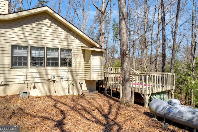 view of property exterior featuring crawl space, a chimney, and a deck