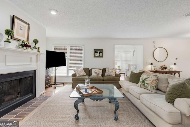 living room with a fireplace with flush hearth, a textured ceiling, and crown molding