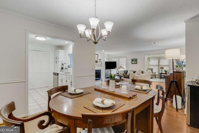 dining space with light tile patterned floors, a notable chandelier, a fireplace, and crown molding