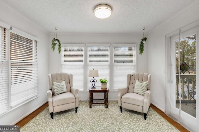 sitting room with a textured ceiling, wood finished floors, and crown molding