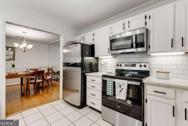 kitchen with backsplash, white cabinets, appliances with stainless steel finishes, and crown molding