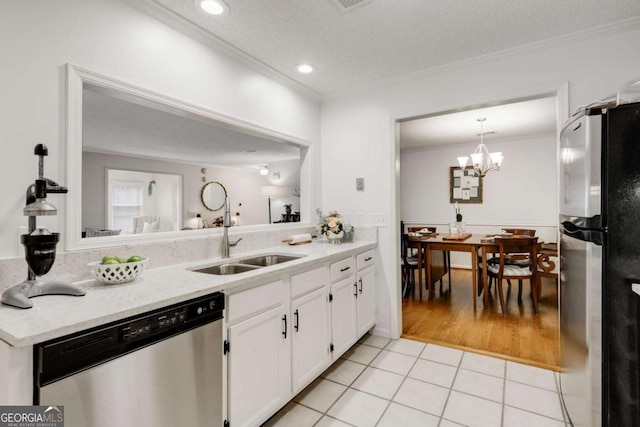 kitchen with light tile patterned flooring, a sink, ornamental molding, stainless steel appliances, and white cabinets