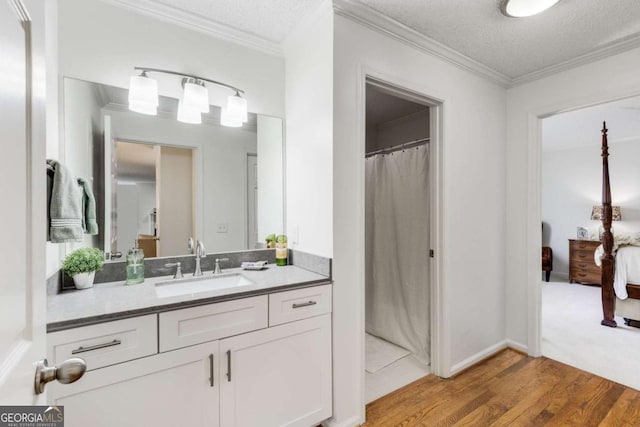 full bath featuring wood finished floors, a textured ceiling, ornamental molding, and vanity