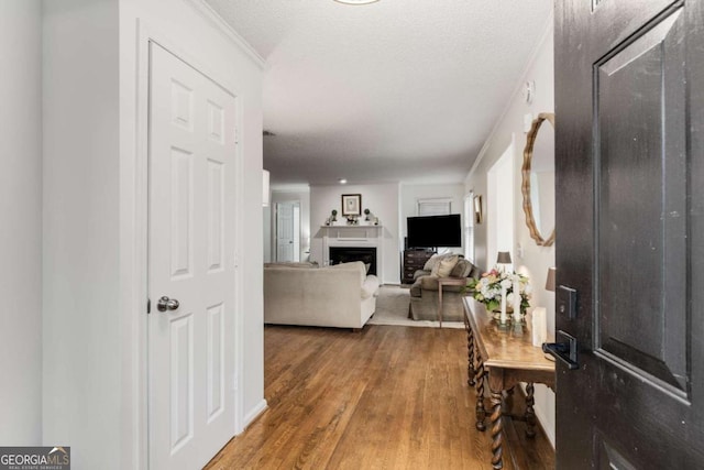 foyer entrance with a textured ceiling, wood finished floors, a fireplace, and crown molding