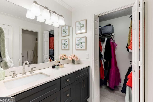 bathroom with a walk in closet, vanity, and crown molding