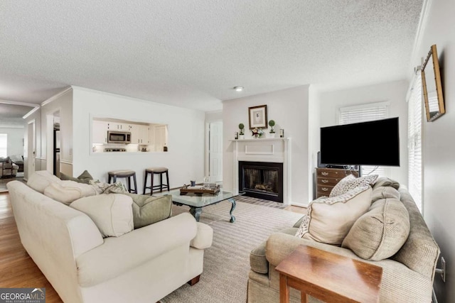 living area featuring a fireplace with flush hearth, wood finished floors, and a textured ceiling