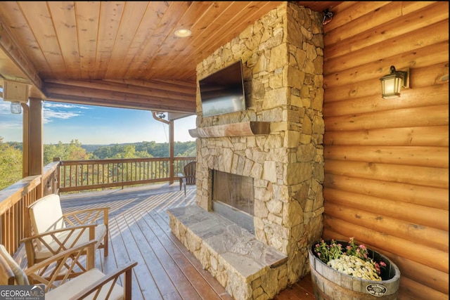 wooden terrace featuring an outdoor stone fireplace