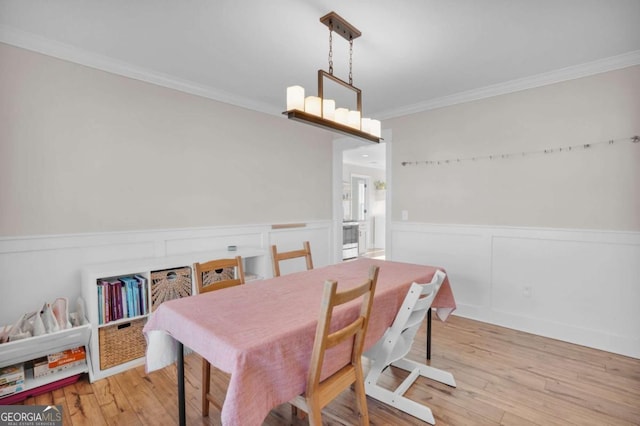 dining room with an inviting chandelier, wood finished floors, a wainscoted wall, and ornamental molding