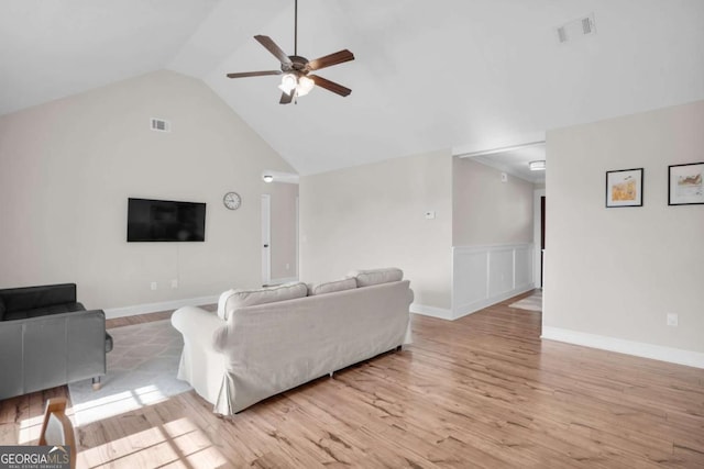 living room featuring light wood-type flooring, visible vents, lofted ceiling, and a ceiling fan