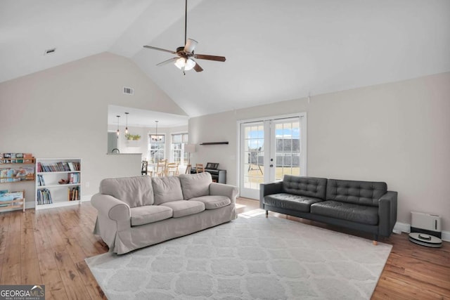 living area with visible vents, baseboards, wood finished floors, high vaulted ceiling, and a ceiling fan