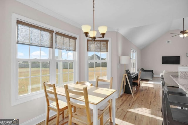 dining area featuring lofted ceiling, a healthy amount of sunlight, light wood-style flooring, and ceiling fan with notable chandelier