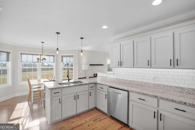 kitchen featuring dishwasher, a peninsula, decorative backsplash, and a sink