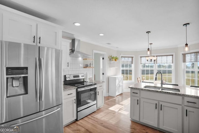 kitchen with a sink, crown molding, wall chimney exhaust hood, and stainless steel appliances