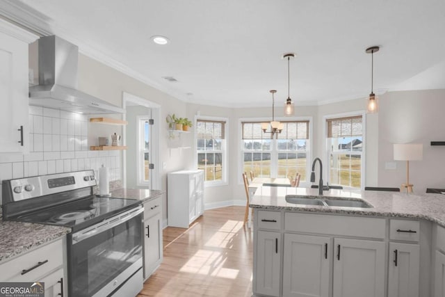 kitchen with a sink, stainless steel electric stove, ornamental molding, and wall chimney range hood