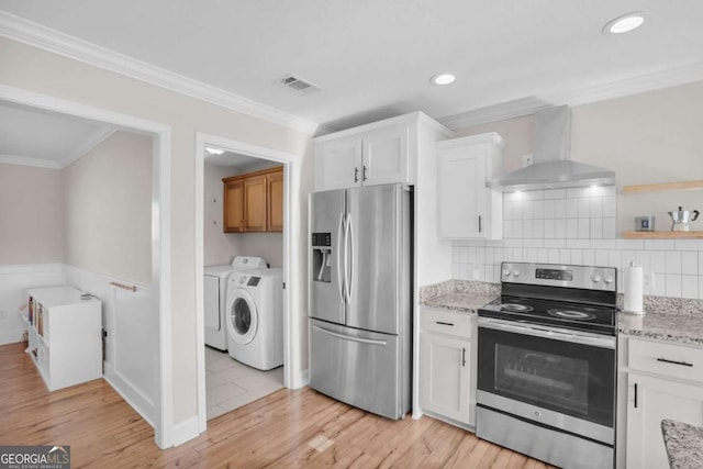 kitchen with visible vents, washer and clothes dryer, appliances with stainless steel finishes, wall chimney exhaust hood, and crown molding