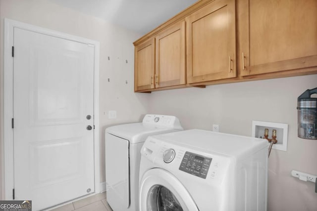 clothes washing area featuring light tile patterned floors, cabinet space, and washing machine and clothes dryer