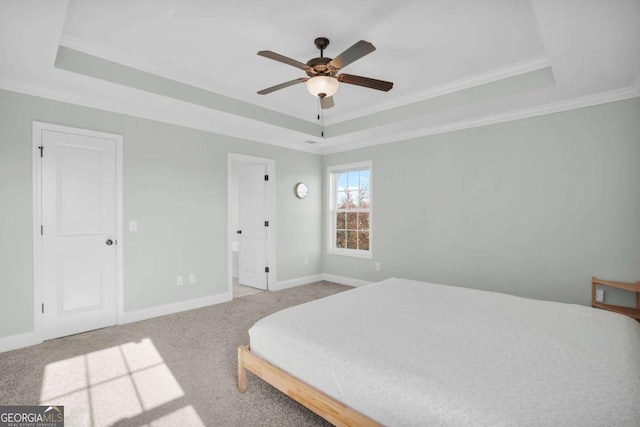 bedroom with ornamental molding, a ceiling fan, a tray ceiling, carpet flooring, and baseboards