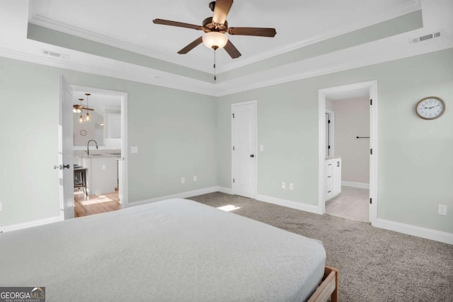 bedroom featuring light carpet, visible vents, crown molding, and a tray ceiling