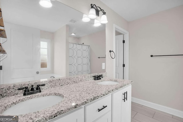 bathroom featuring double vanity, a shower with curtain, baseboards, and a sink