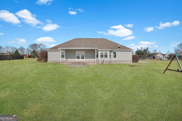 back of property with fence, french doors, and a lawn