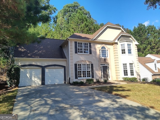 view of front of property featuring a front lawn, concrete driveway, roof with shingles, stucco siding, and a garage