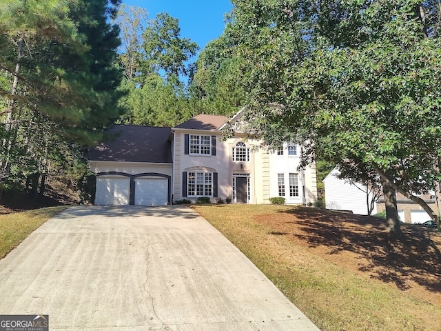 colonial house featuring an attached garage, concrete driveway, and a front yard