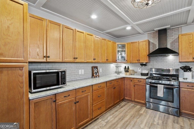 kitchen with beam ceiling, light wood-style flooring, stainless steel appliances, decorative backsplash, and wall chimney exhaust hood