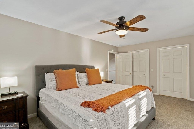 carpeted bedroom featuring two closets, baseboards, and a ceiling fan