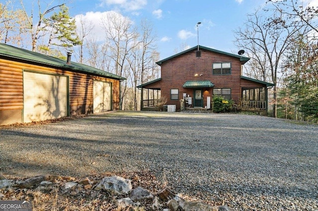 back of property with central air condition unit, a detached garage, an outbuilding, and faux log siding