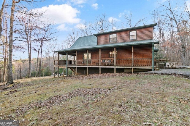 rear view of property with faux log siding, a porch, and metal roof