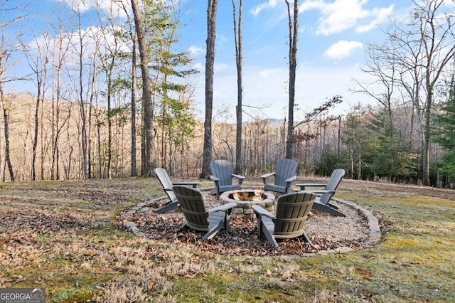 view of yard with an outdoor fire pit and a forest view