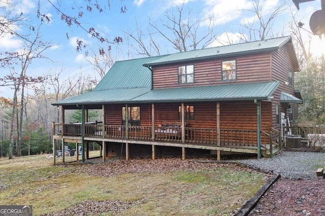 rear view of house with log veneer siding, cooling unit, and metal roof