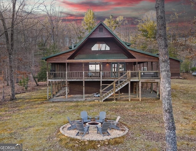 back of property at dusk featuring a fire pit, stairs, and a deck