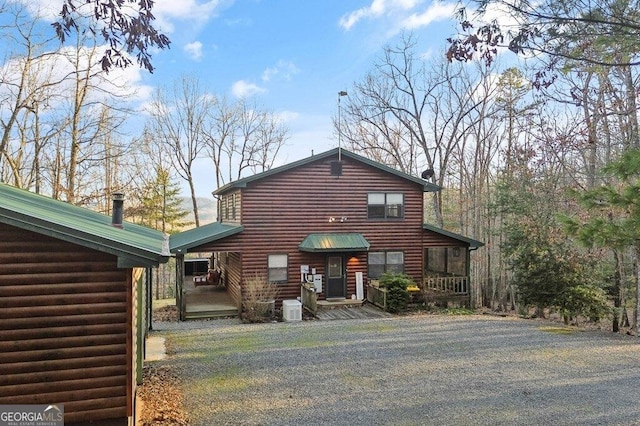 view of front of property featuring gravel driveway and log veneer siding