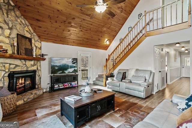 living room featuring wood ceiling, a stone fireplace, wood finished floors, and stairs