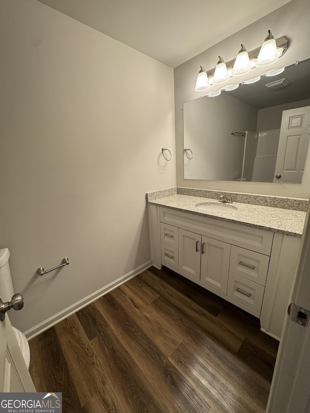 bathroom with vanity, wood finished floors, and baseboards