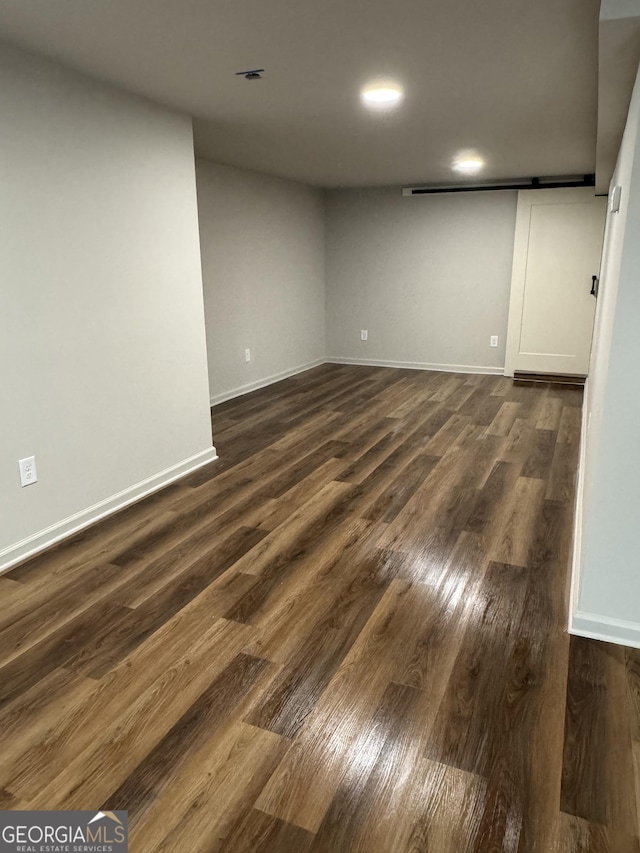 interior space featuring a barn door, dark wood-style floors, and baseboards