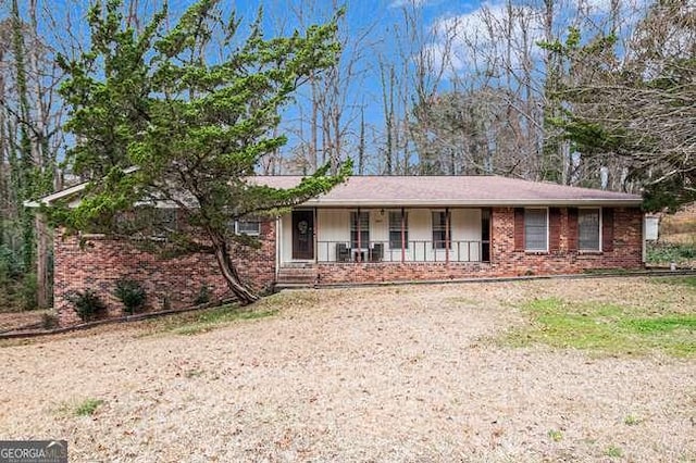 ranch-style house featuring a porch, brick siding, and driveway