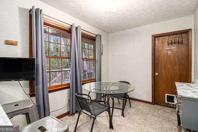 dining room with a textured wall, baseboards, and a textured ceiling