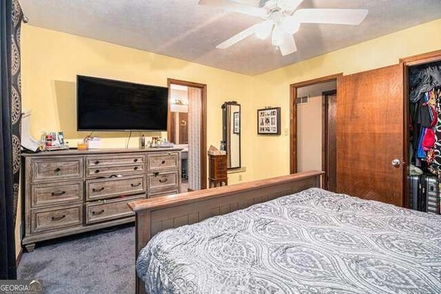 bedroom featuring a ceiling fan, dark colored carpet, a closet, and a textured ceiling