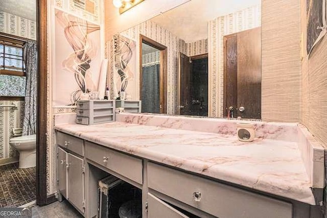 bathroom featuring toilet, vanity, and wallpapered walls