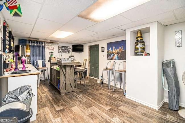 dining space with wood finished floors, baseboards, and a paneled ceiling