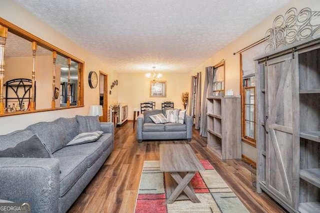 living area with a notable chandelier, a textured ceiling, and wood finished floors