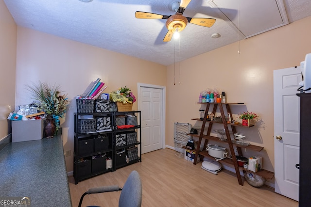 miscellaneous room featuring a textured ceiling, attic access, wood finished floors, and a ceiling fan