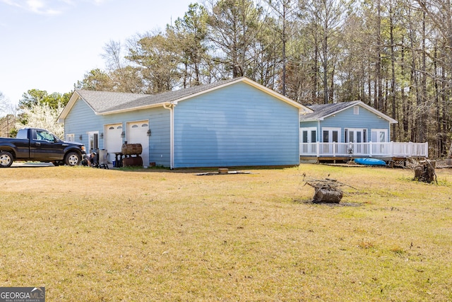 back of property featuring a yard, a garage, and a wooden deck